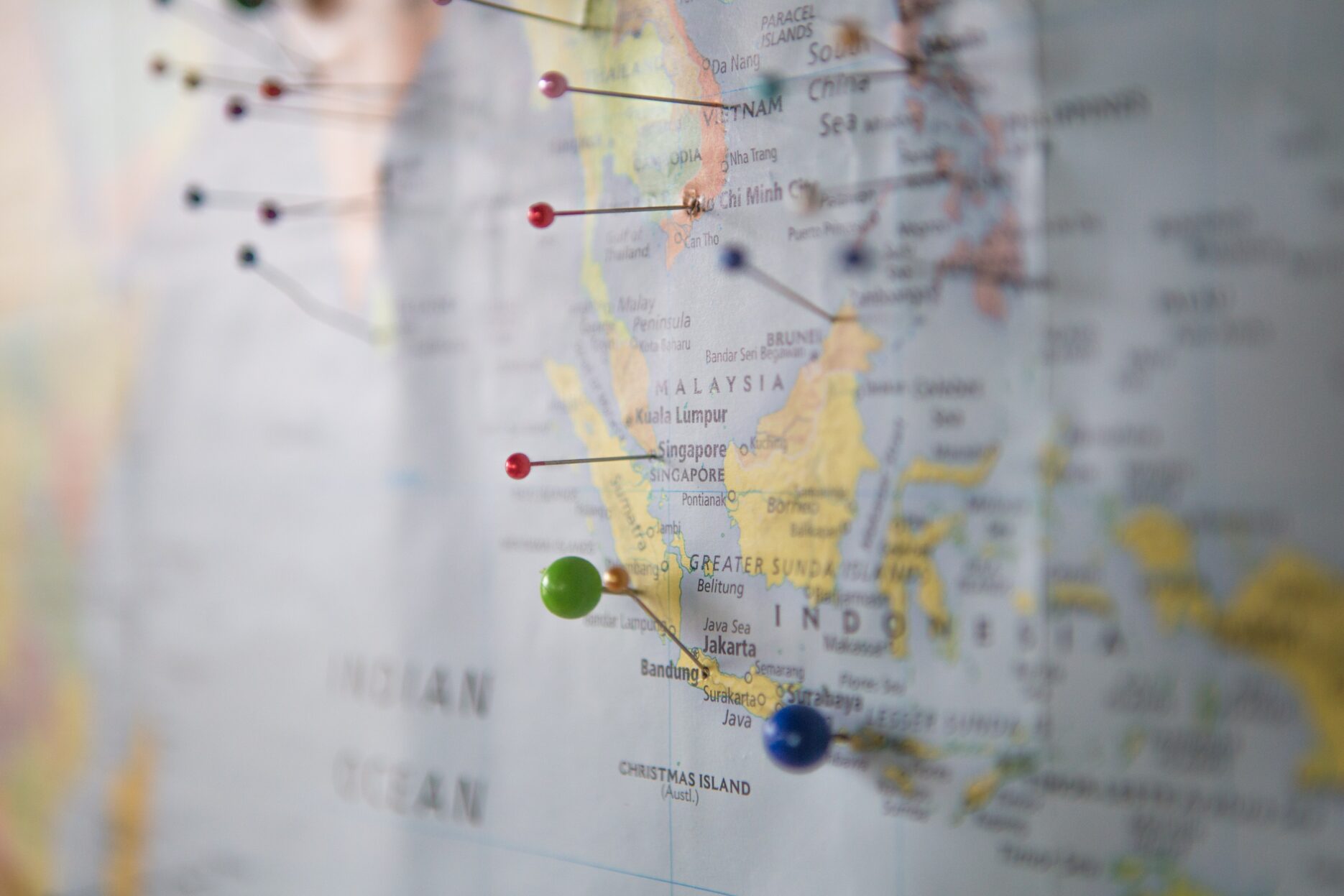 A blurred map with pins stuck in it; in focus is Indonesia.
