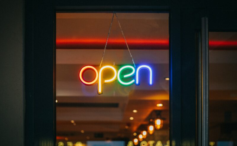 A rainbow sign reads "open" in neon light.