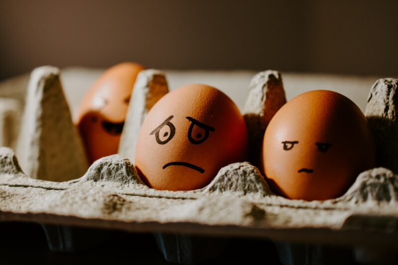 Two brown eggs in an egg carton have been decorated to look quite worried.